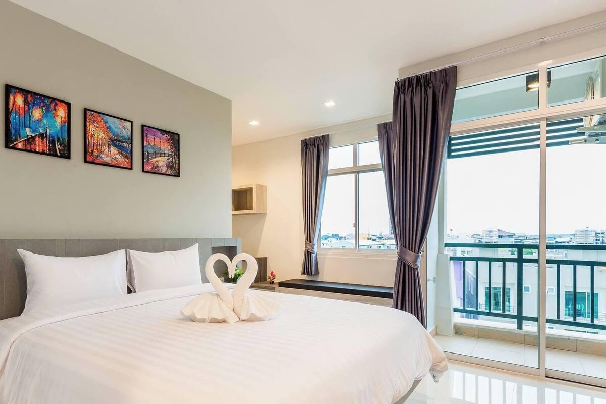 Une chambre d’hôtel avec un grand lit, une vue sur la ville et trois tableaux accrochés au mur.