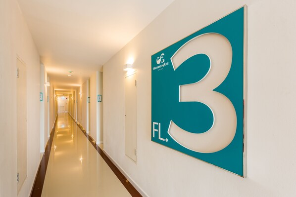 A hallway with a teal sign indicating room number 3.