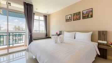 A hotel room with a large bed, a nightstand, a window with curtains, and three framed pictures on the wall.