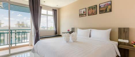 Habitación de hotel con una cama grande, una mesita de noche, un ventanal con cortinas y tres cuadros enmarcados en la pared.