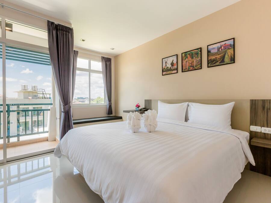 A hotel room with a large bed, a nightstand, a window with curtains, and three framed pictures on the wall.