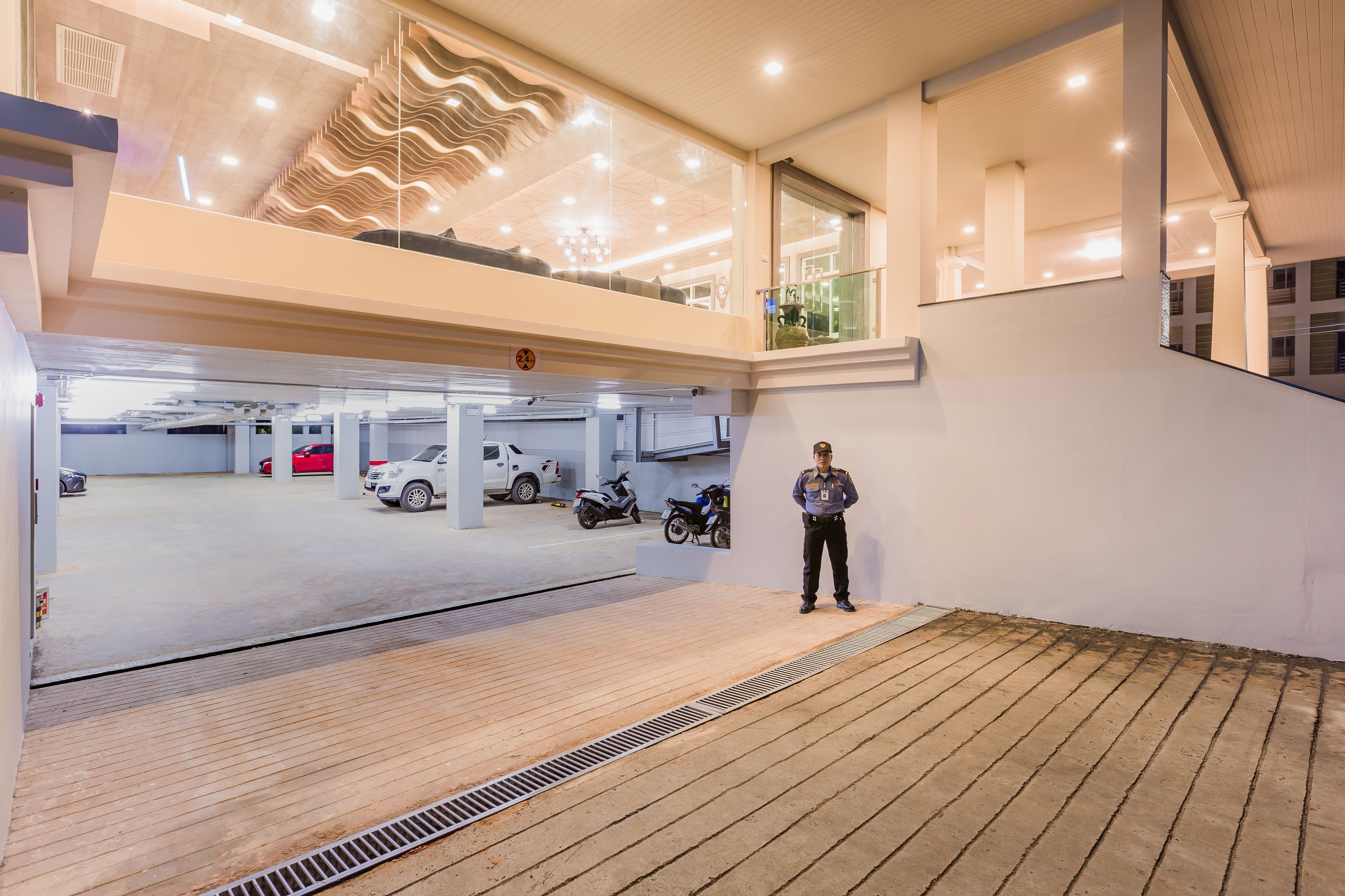 A modern building with a multi-level parking garage, a person standing on the upper level, and a distinctive ceiling design.