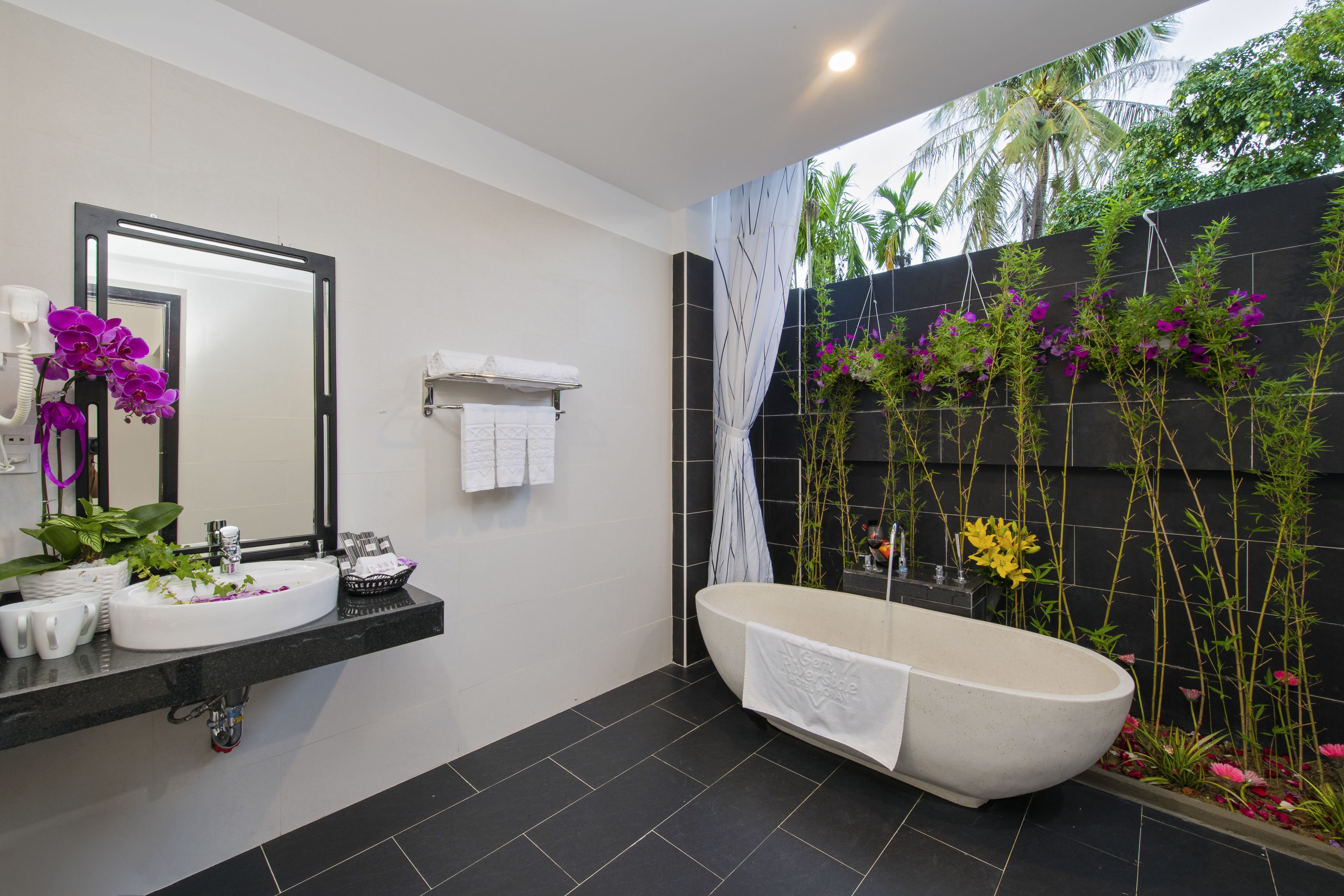 A modern bathroom with a freestanding bathtub, a large mirror, and a wall-mounted sink.