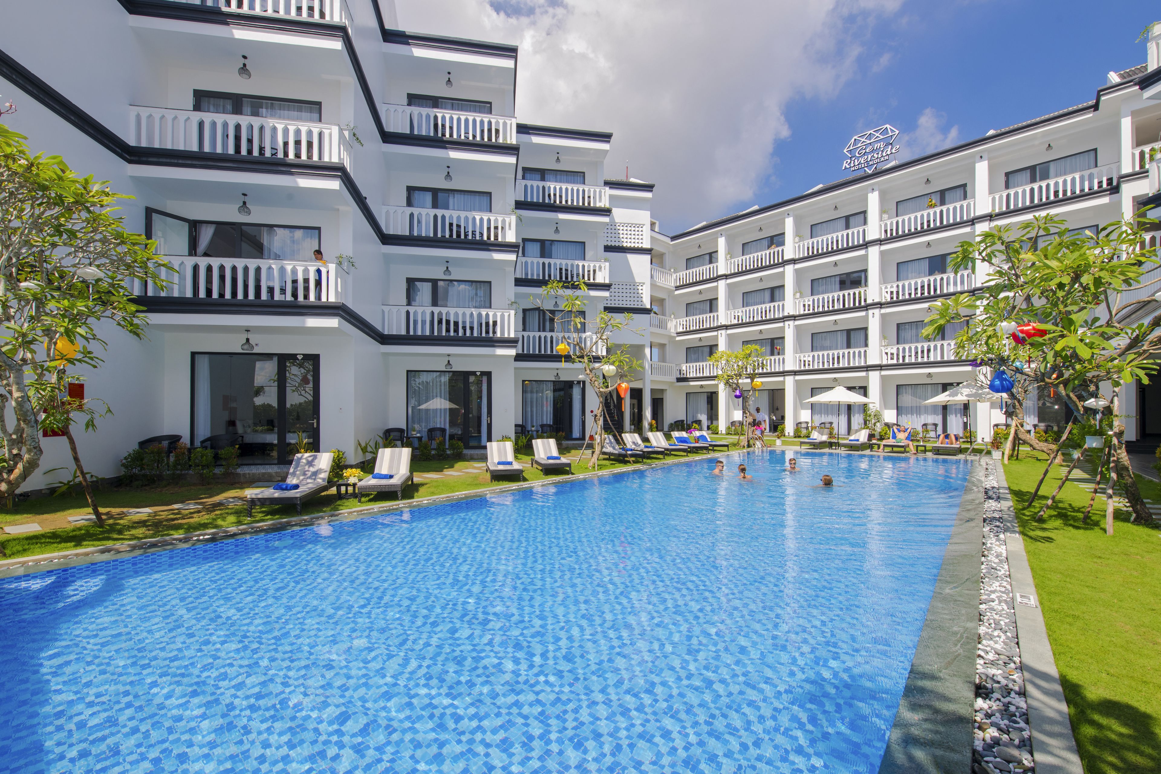 Un hotel con piscina, varios balcones y cielo despejado.