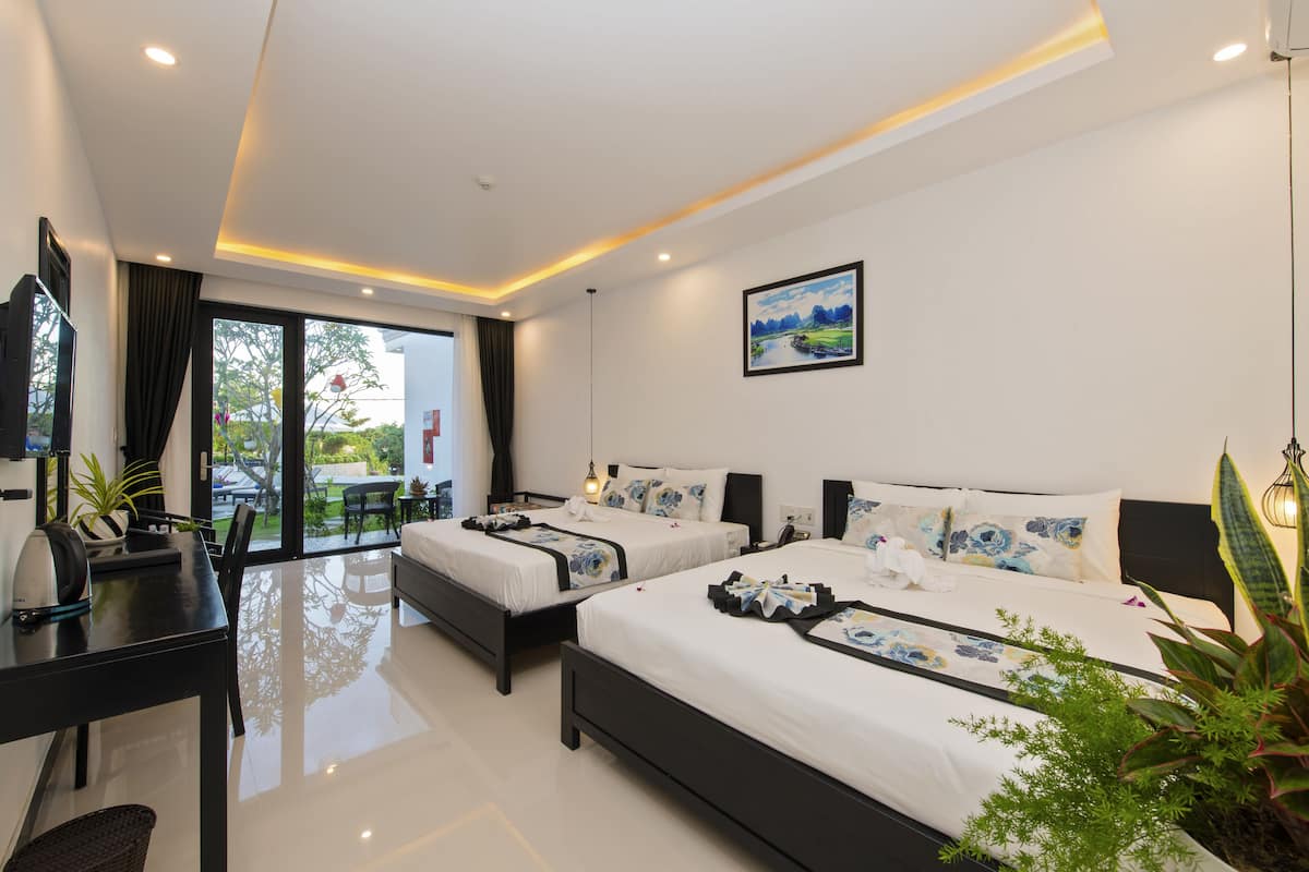 A modern hotel room with two beds, a dining area, and a large window with a view of the outdoors.