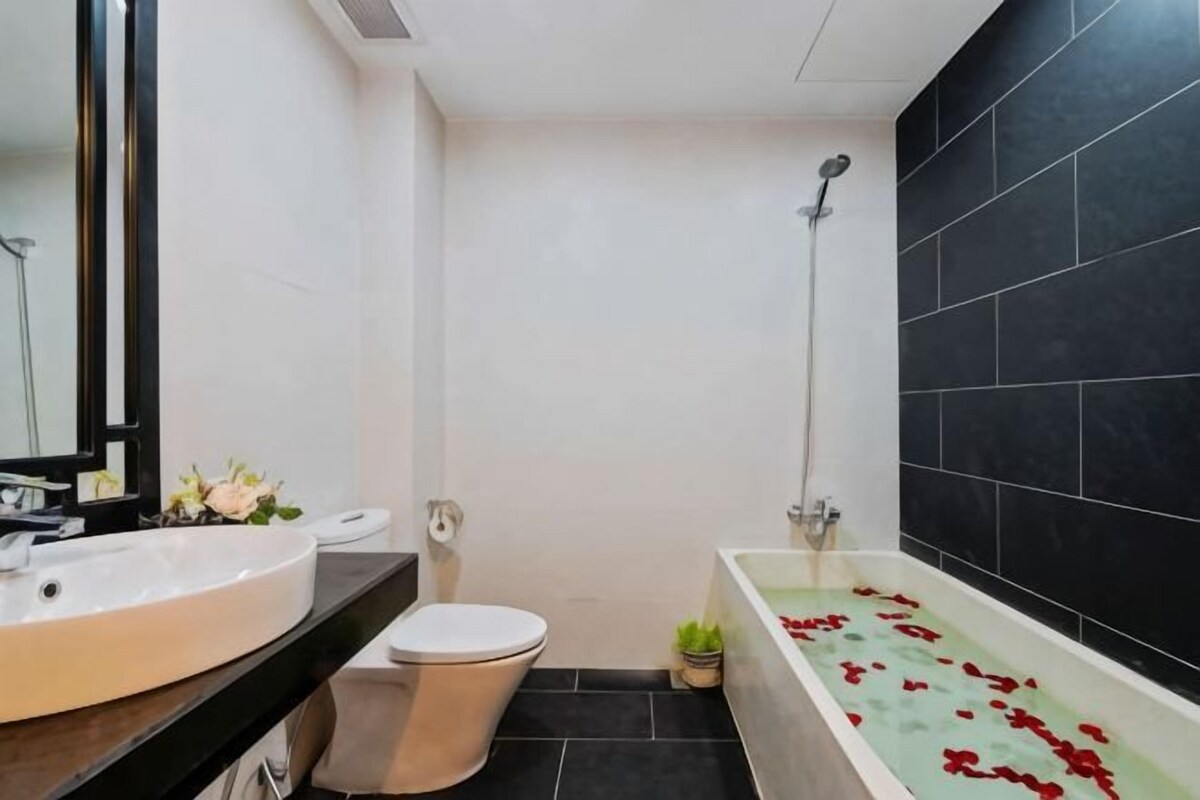 A bathroom with a white sink, toilet, and bathtub with rose petals.