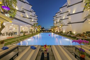 Een buitenzwembad, parasols bij het zwembad en ligstoelen