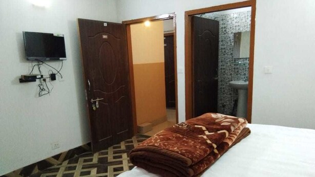 A hotel room with a bed, a television mounted on the wall, and a bathroom visible through an open door.