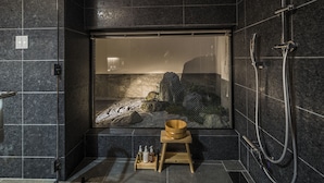A modern bathroom with a large window, a wooden bath mat, and a small wooden tray with toiletries. - Kyoto Shijo Takakura Hotel grandereverie (Kyoto)