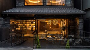 A modern building with a dark facade, large windows, and a well-lit interior. - Kyoto Shijo Takakura Hotel grandereverie (Kyoto)