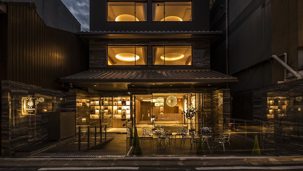 A modern building with a glass facade, a dining area with outdoor seating, and a well-lit entrance. - Kyoto Shijo Takakura Hotel grandereverie (Kyoto)