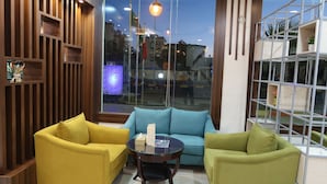 Una sala de estar moderna con un sofá azul, sillones amarillos y una mesa de centro de vidrio.