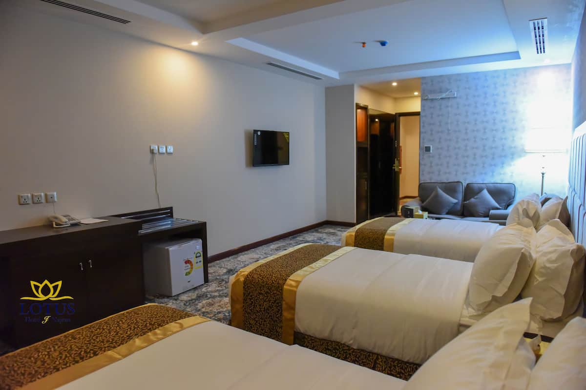 A hotel room with two beds, a desk, a television, and a minibar.