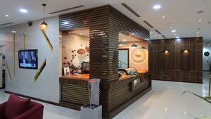 Una moderna zona de recepción con estación de café, una pantalla de televisión y una pared decorativa.