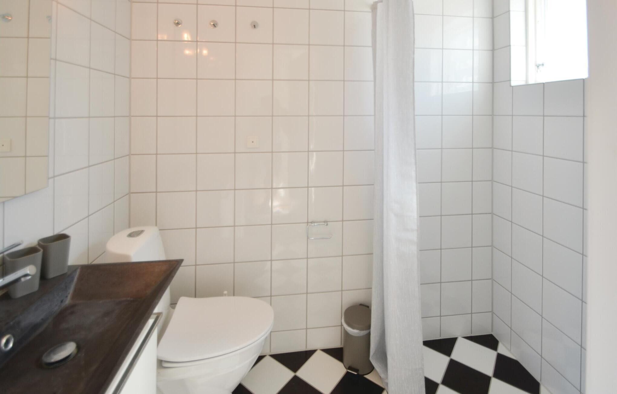 Une petite salle de bain avec des carreaux blancs, des toilettes, un lavabo et un rideau de douche.