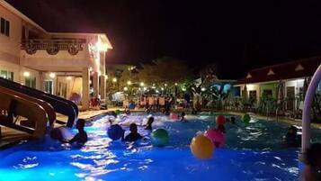 Zona de piscina con tobogán y gente usando pelotas inflables.