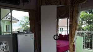 Une chambre avec un lit, un bureau, un réfrigérateur et une fenêtre avec des rideaux.