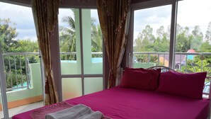 Une chambre d’hôtel avec un lit, des rideaux et une vue sur la verdure et les bâtiments.