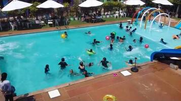 A swimming pool with multiple lanes, surrounded by umbrellas and chairs, indicating a poolside area.