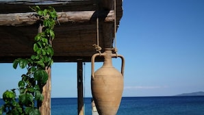 Una maceta de barro colgando bajo una estructura de madera junto al mar.