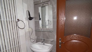 Un baño con un lavabo blanco, un espejo y una zona de ducha.