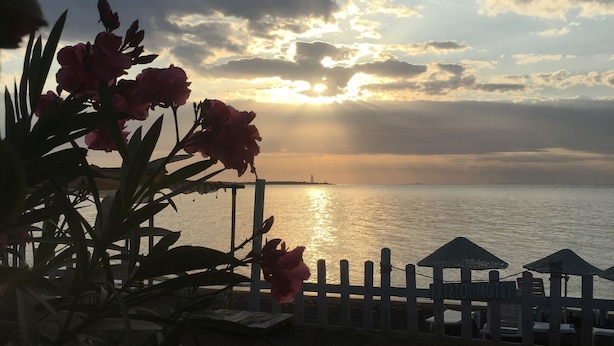 Vista del atardecer con playa y una valla con sombrillas.