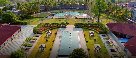 A resort with a central pool, multiple guest huts, and surrounding palm trees.