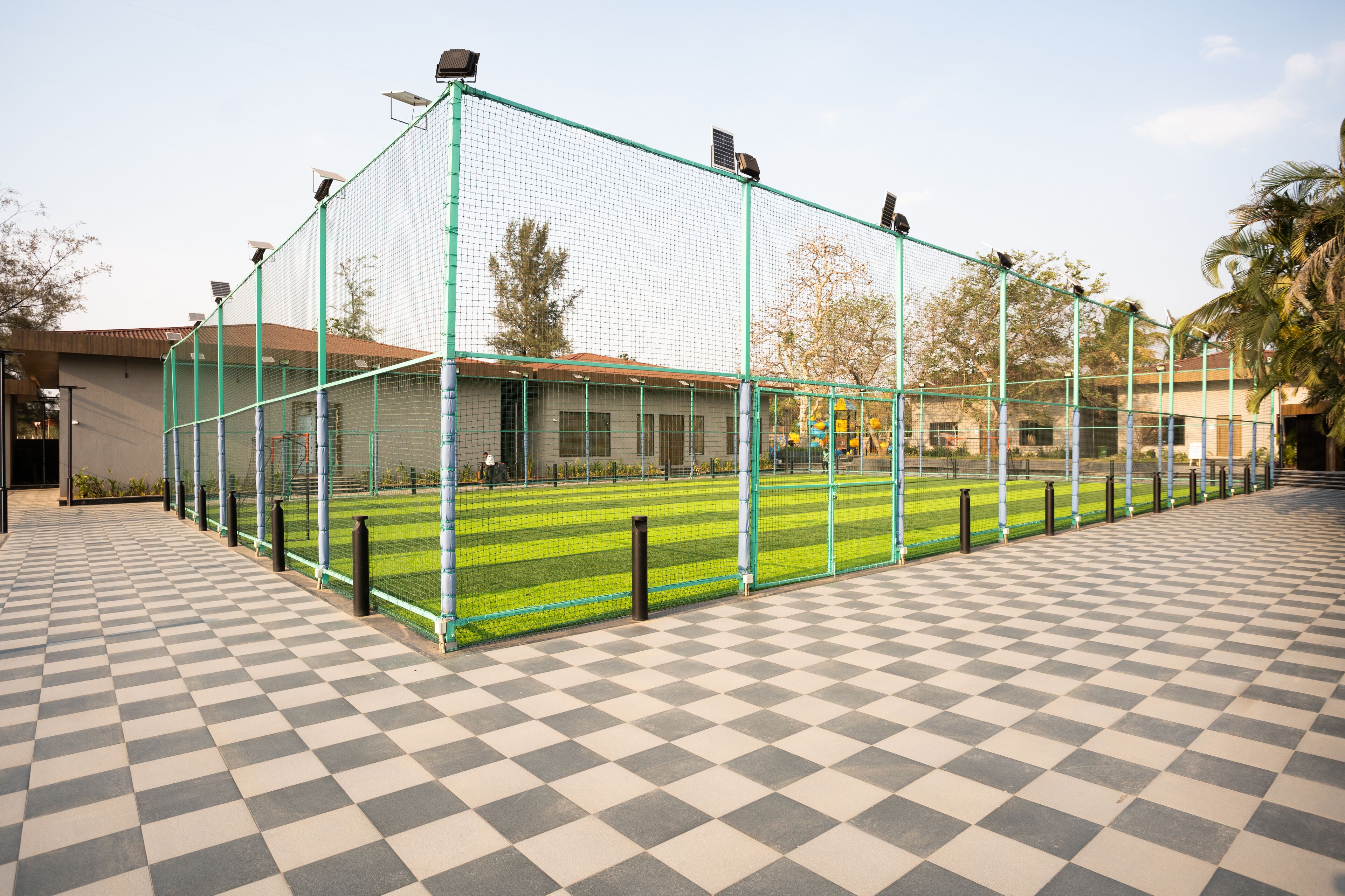 A sports field enclosed by a green fence with a checkered floor.