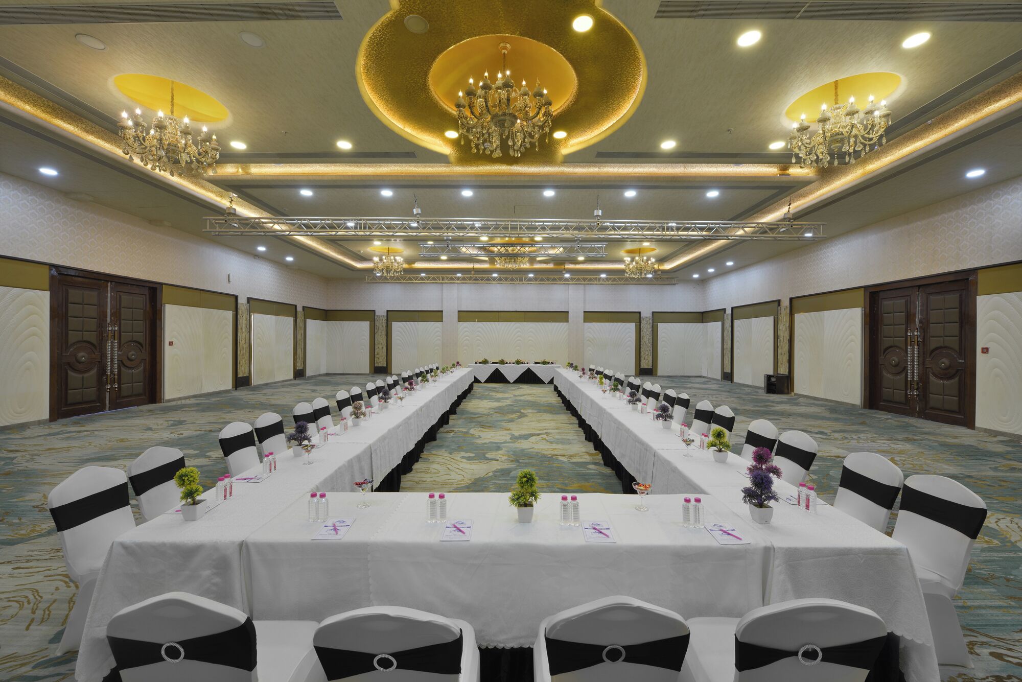Une salle de conférence avec une longue table, des chaises noires et blanches, et des lustres.