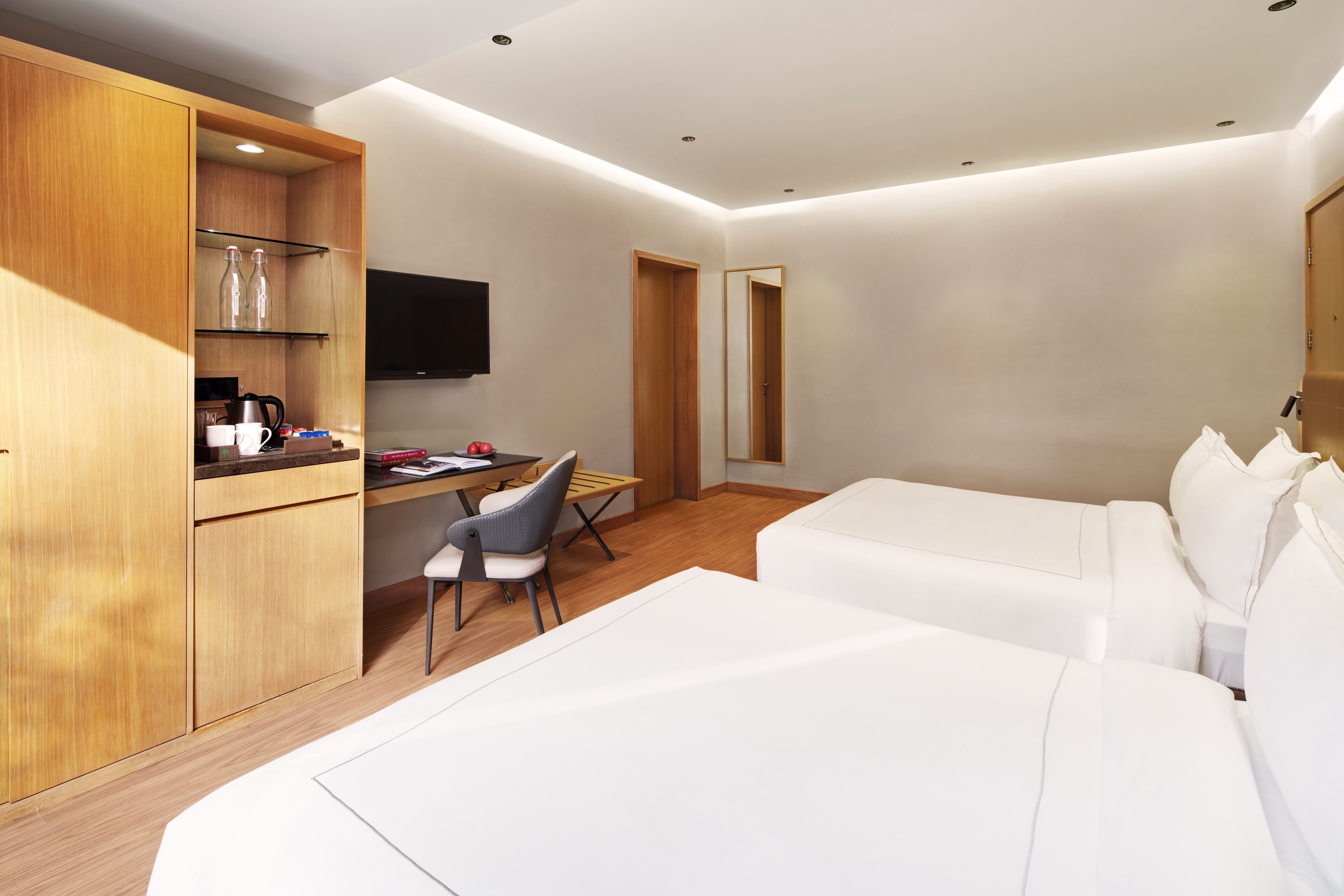 Una habitación de hotel con cama, escritorio, silla, televisor y armario de madera.