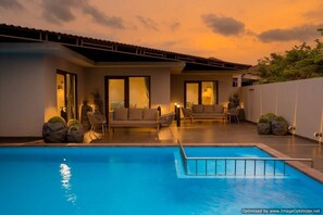 A modern outdoor pool area with a sofa and chairs, a covered seating area, and a clear sky. - Treat Resort (Silvassa)