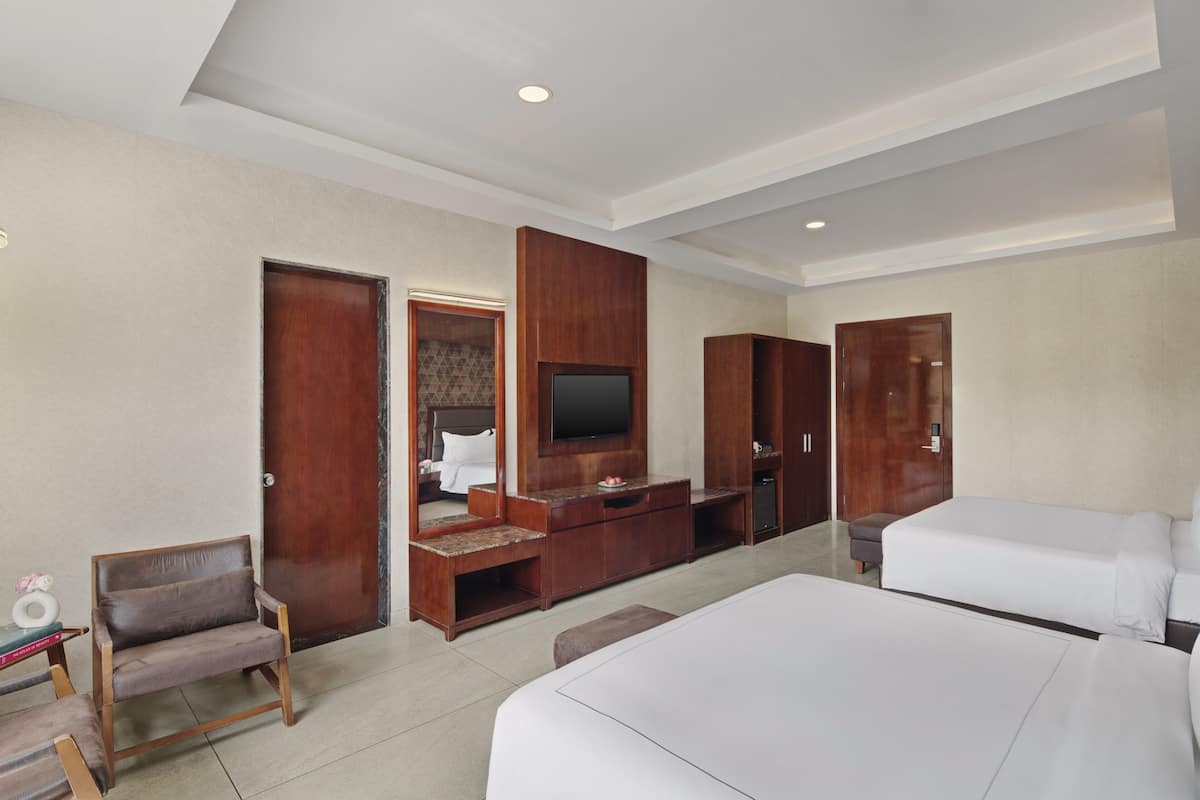 Habitación de hotel con una cama grande, televisión, muebles de madera y puerta de baño.