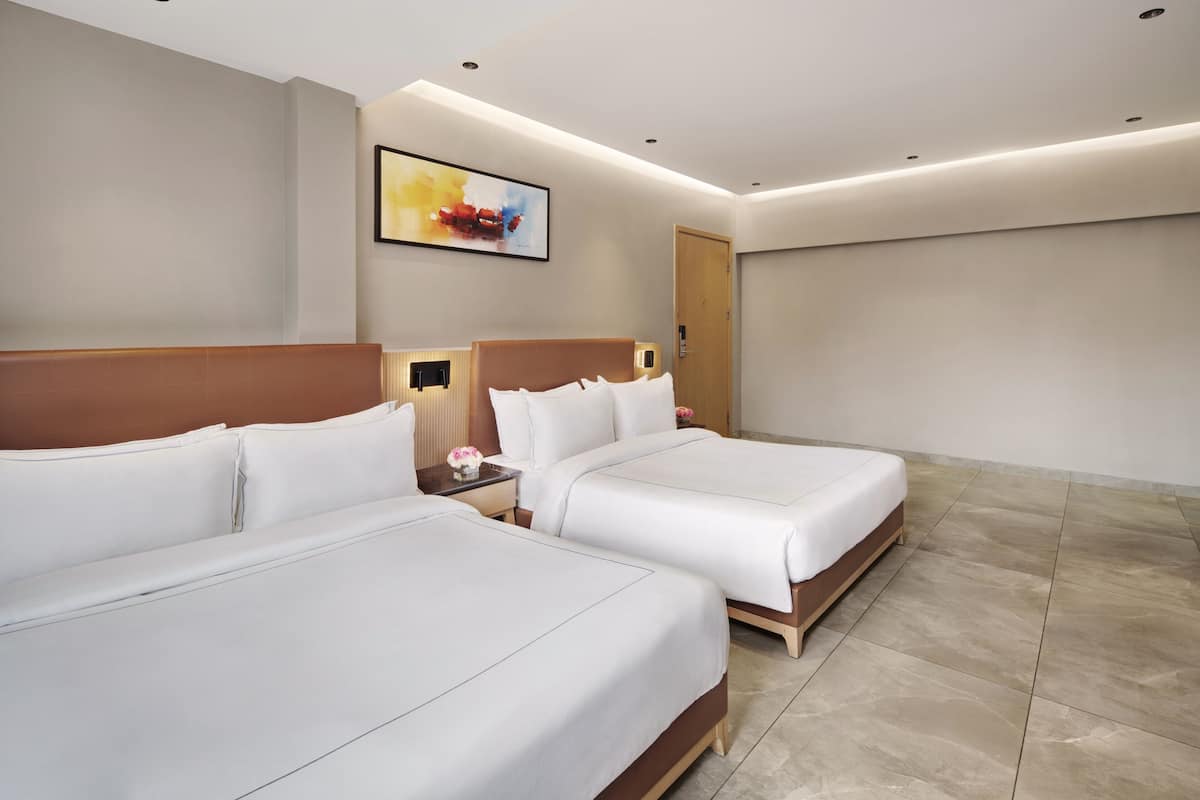 Una habitación de hotel con dos camas, un cuadro en la pared y una puerta.