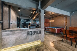 Un área de recepción con mesa de billar y mesa de futbolín al fondo.