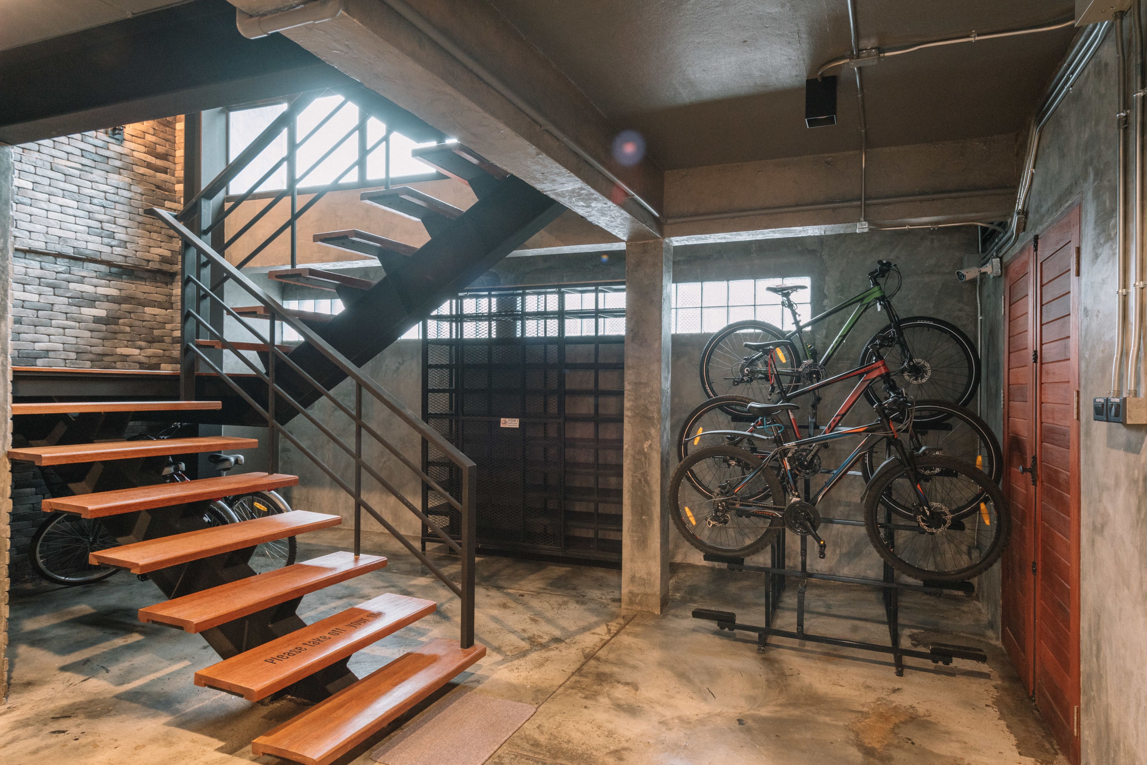 A staircase with wooden steps leading to a loft area, a bicycle rack with a bike, and a garage door.