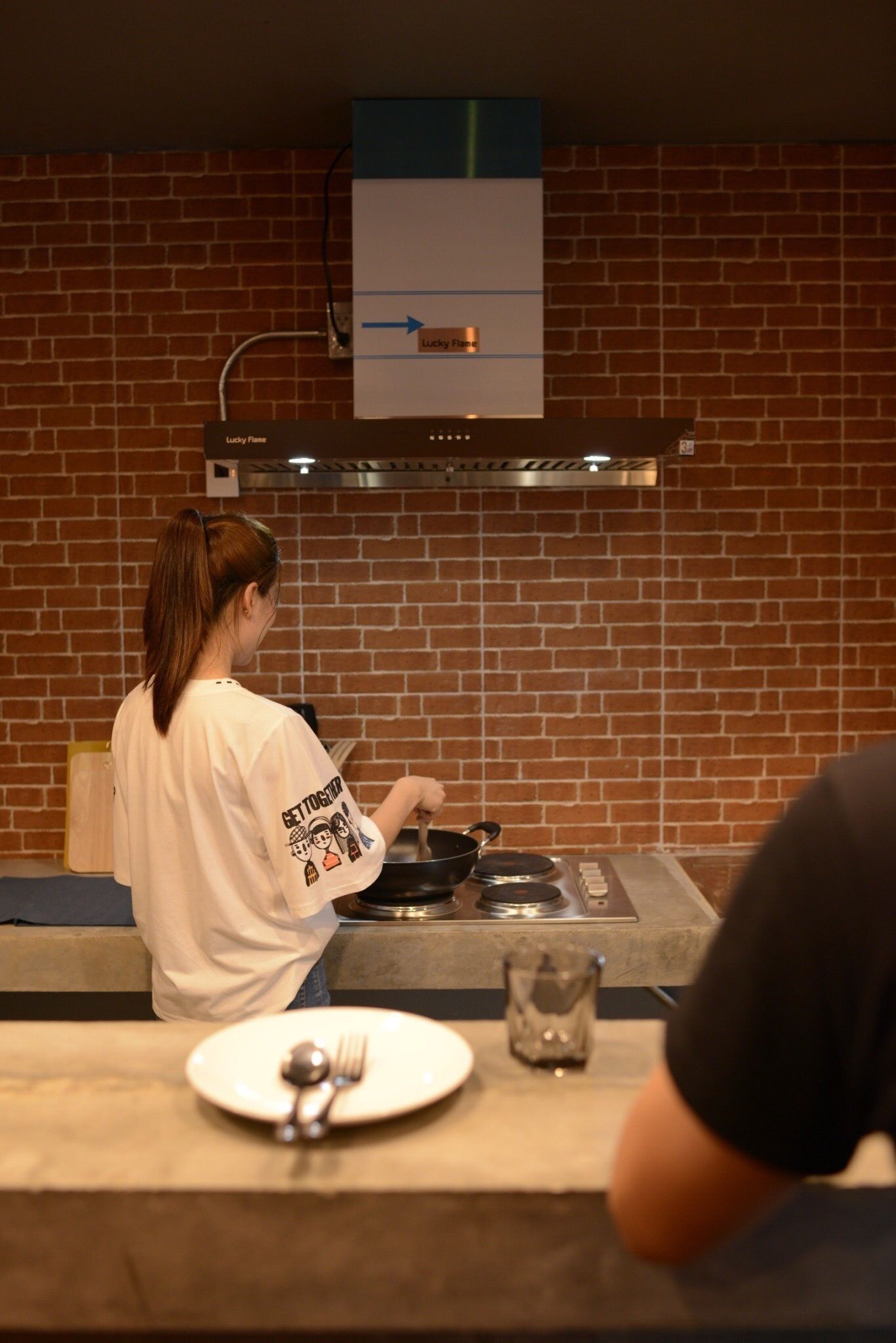 Una persona cocina en una cocina con pared de ladrillo y estufa.