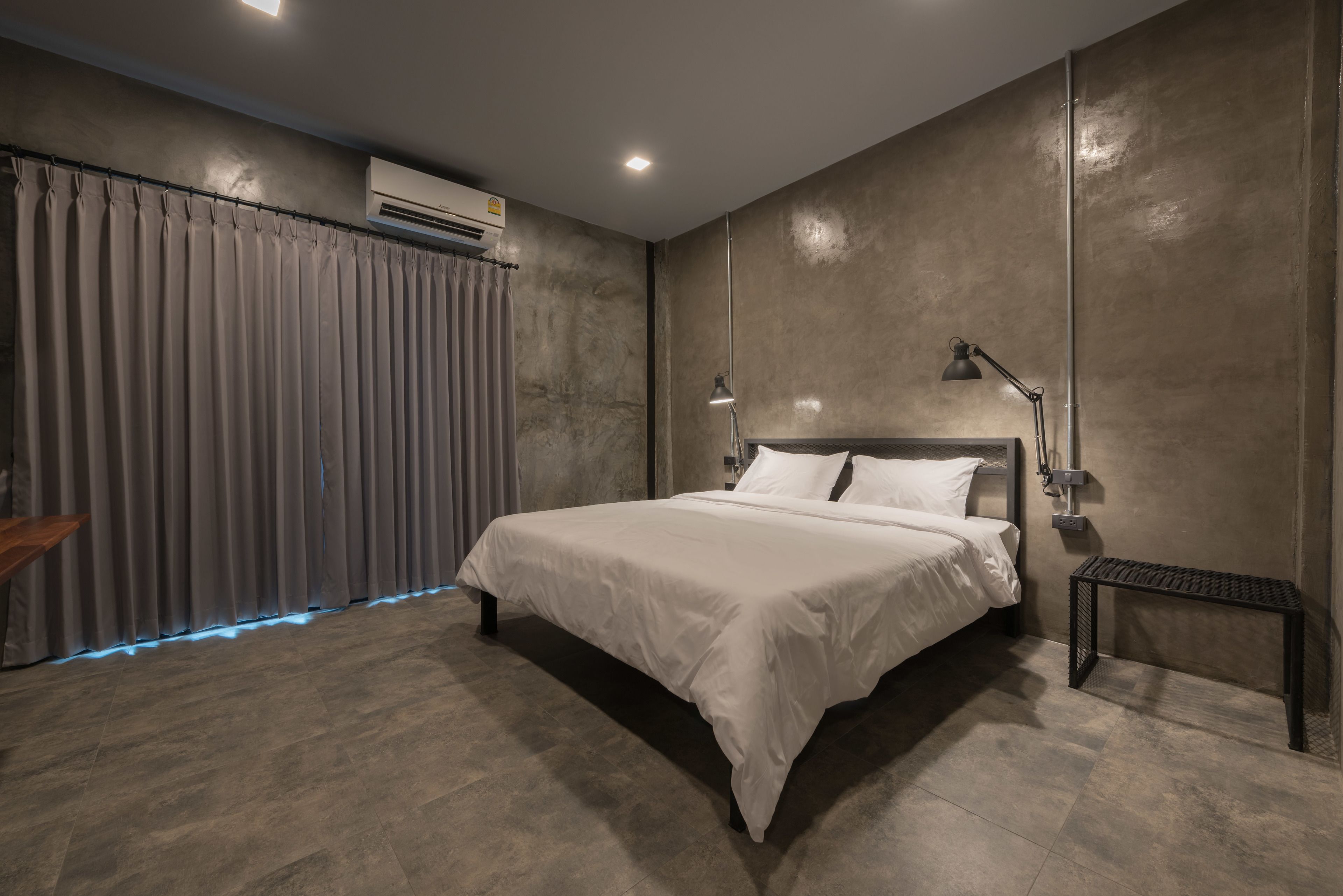 A modern bedroom with a large bed, a bedside table, a lamp, and a curtain.