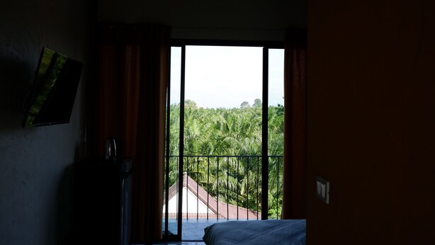 Quarto com uma grande janela com vista para uma paisagem verdejante.