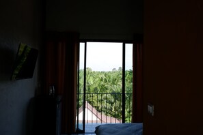 A bedroom with a large window overlooking a lush green landscape. - Black Elephant Boutique (Phunphin)