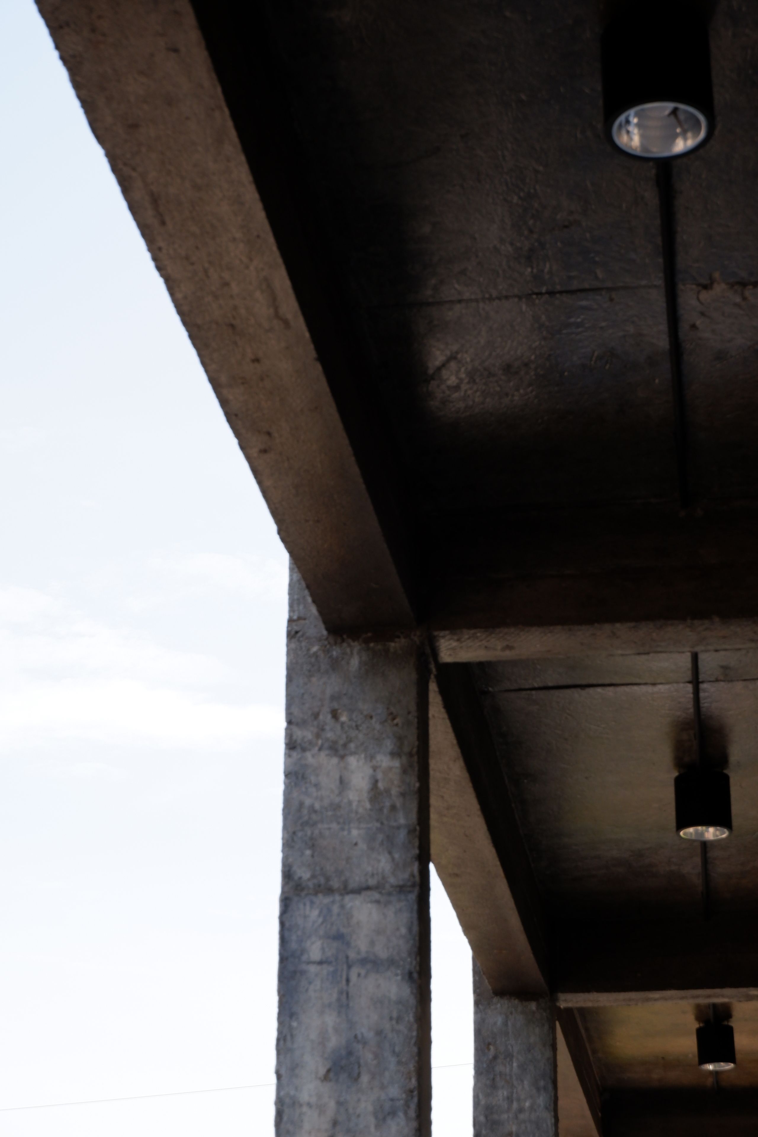 A concrete ceiling structure with visible beams and hanging lights.
