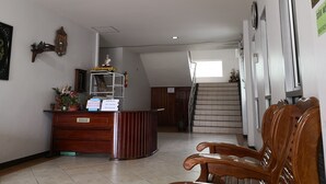 Un área de recepción con un escritorio de madera, una estatua y una escalera que sube.
