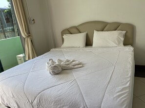 A neatly made bed with a white duvet and a towel arranged in a swan shape. - View Inn (Seka)