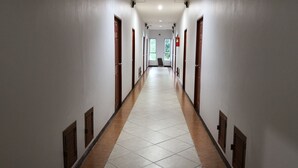 Un pasillo largo y estrecho con paredes blancas y puertas de madera.
