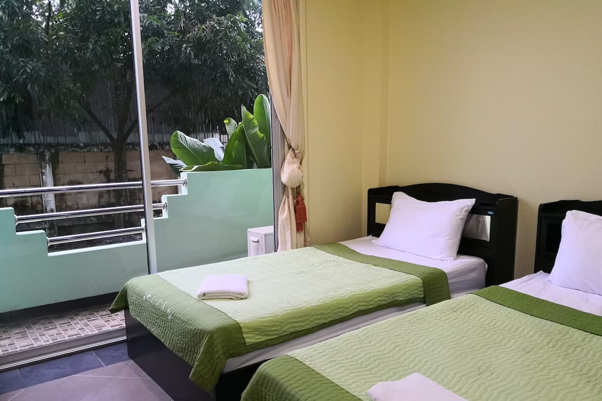 Quarto de hotel com duas camas, varanda e vista para árvores.