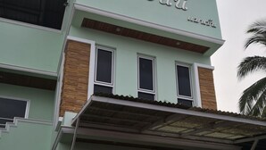 Un edificio de dos pisos con fachada verde clara y un letrero que dice "โรงแรม".