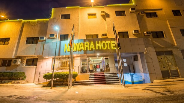 L’entrée d’un hôtel, avec une enseigne indiquant « Nuwara Hotel » et un escalier menant à l’entrée.