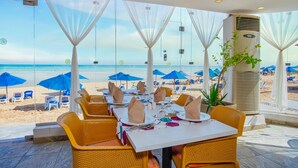 Un restaurant situé en bord de mer, avec des chaises et des tables en osier disposées pour les repas, offrant une vue sur l’océan.