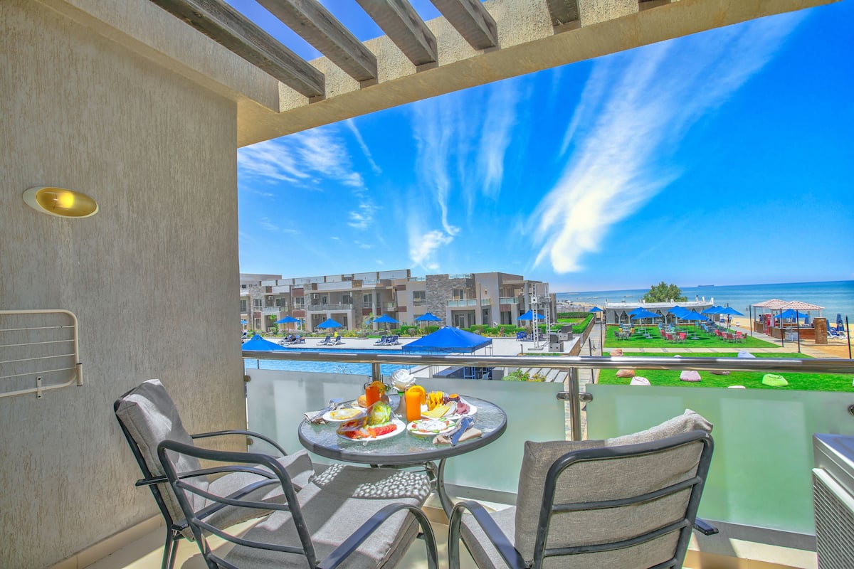 Een balkon met een ontbijttafel, met uitzicht op een zwembad en het resort.