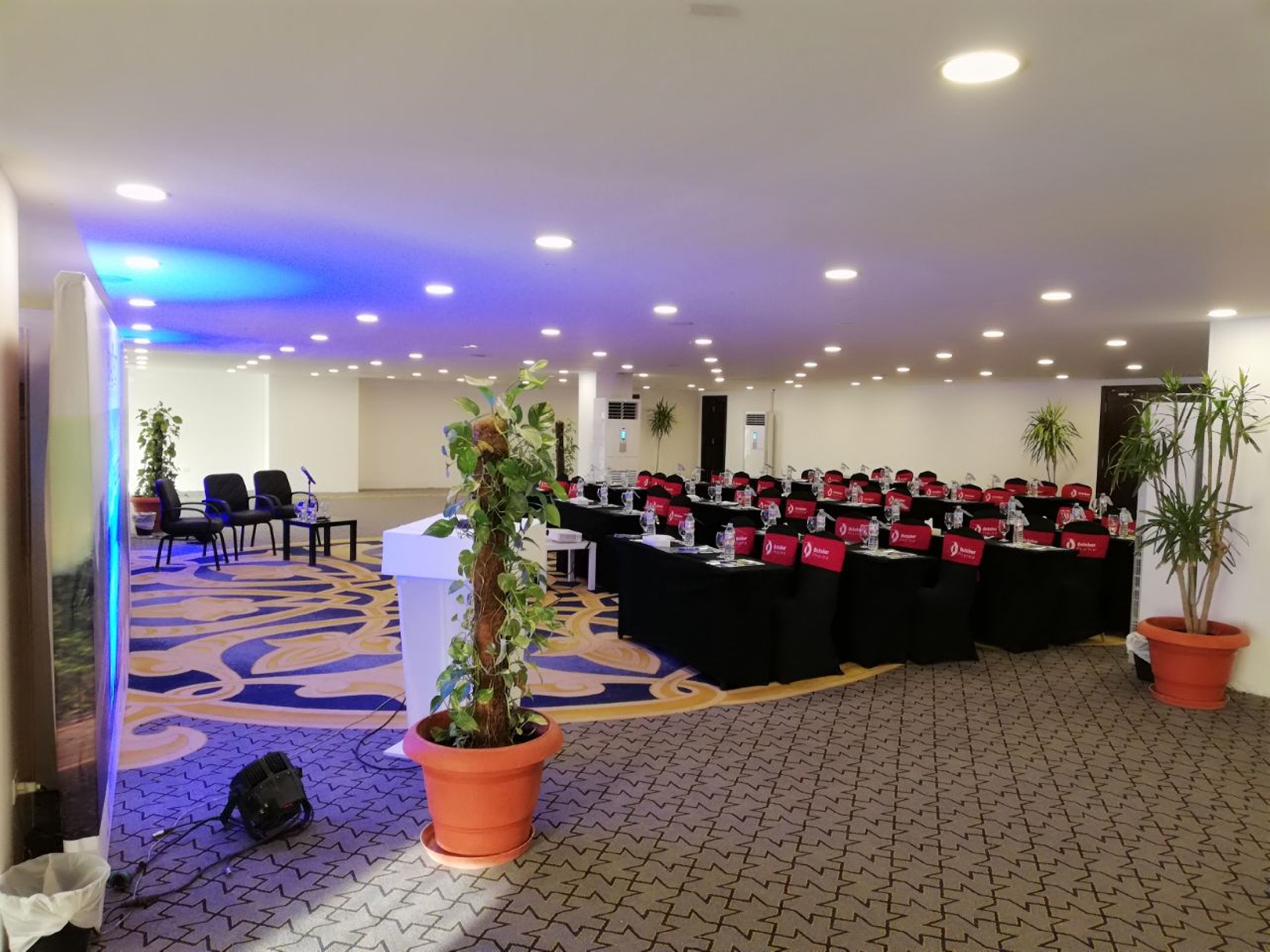 A conference room with tables, chairs, and potted plants.