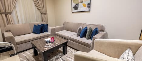A living room with two sofas, a coffee table, and a framed abstract painting on the wall.